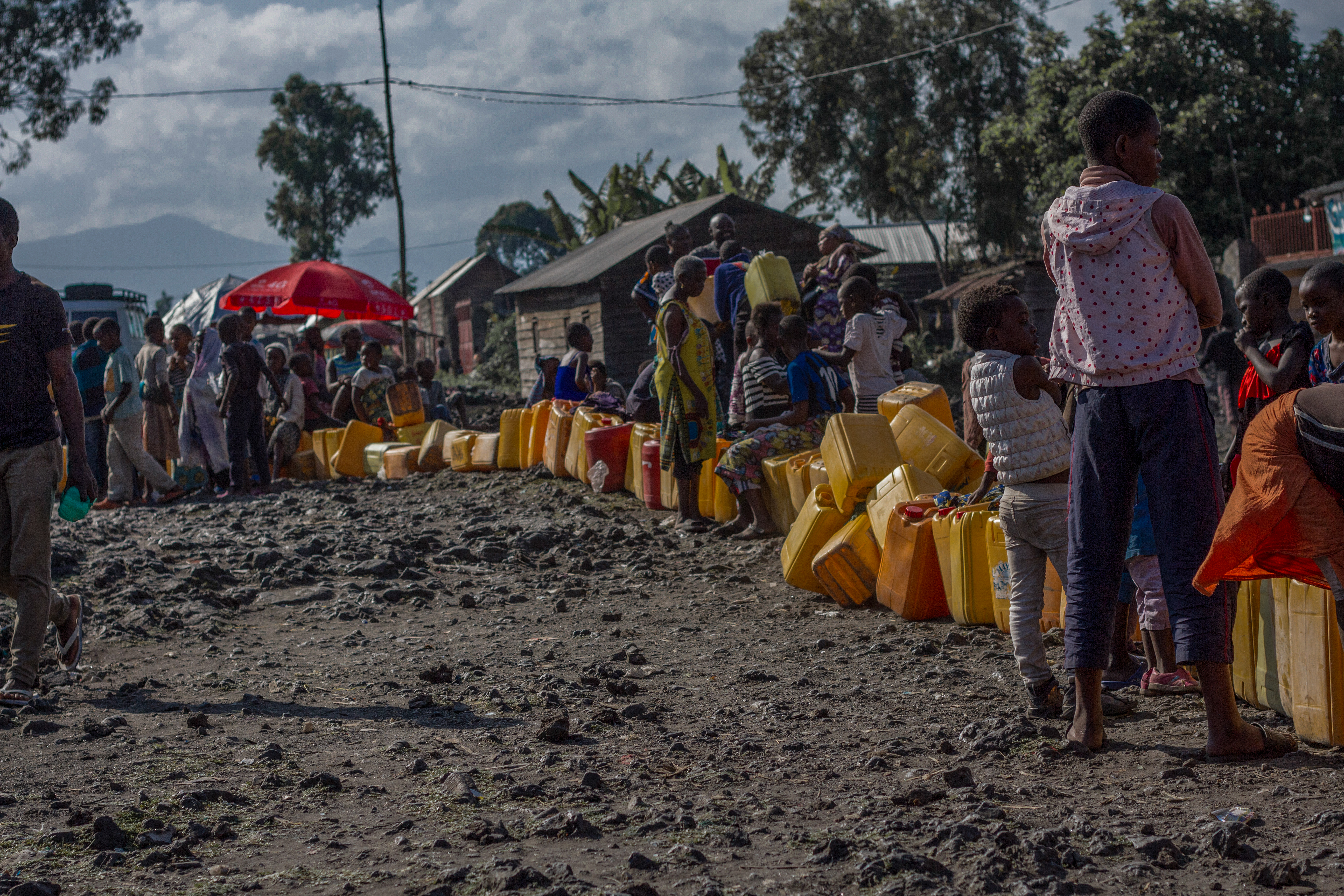 Adults and children wait along a line of jerry cans in Goma.