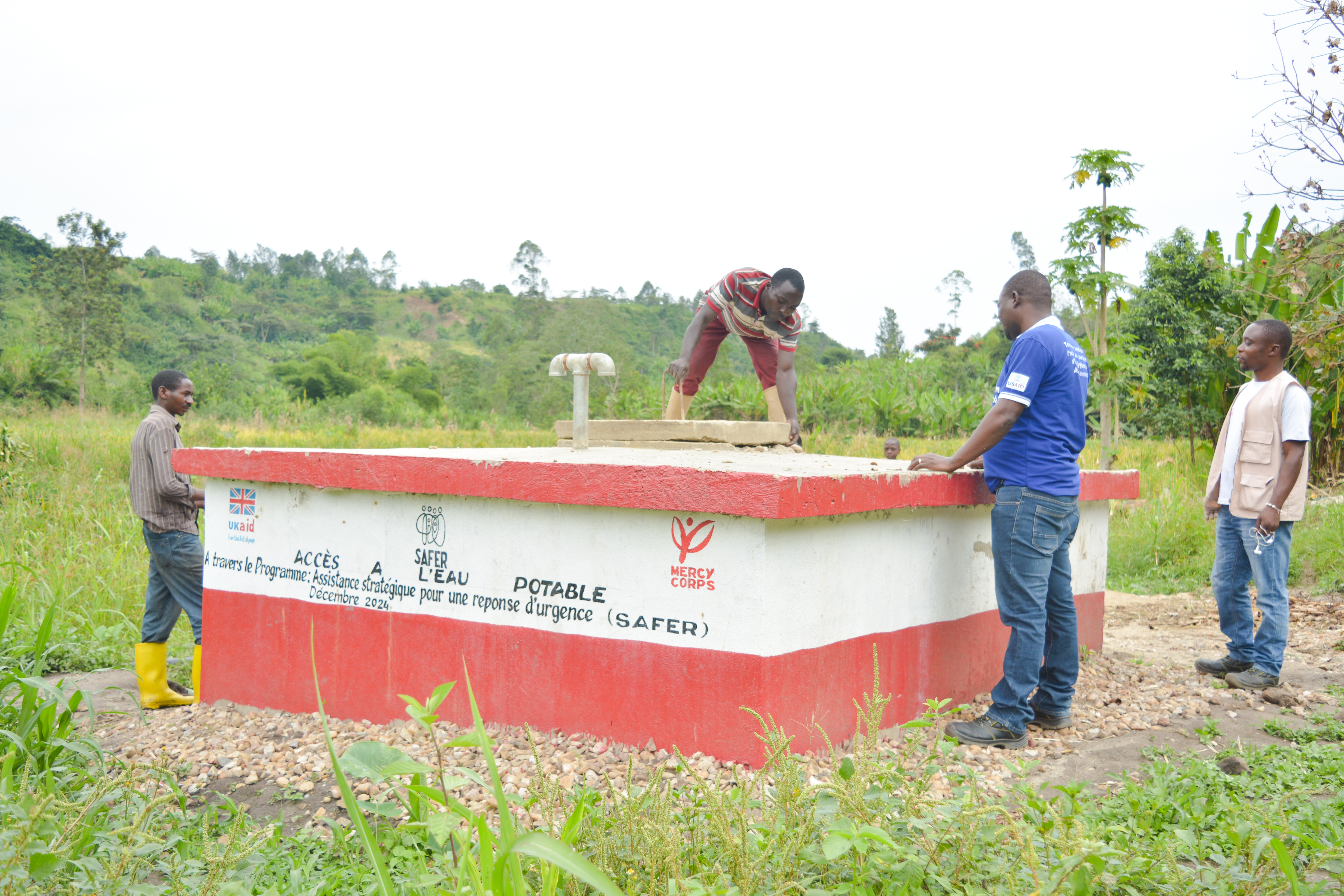 Four men work on a potable water well facility.