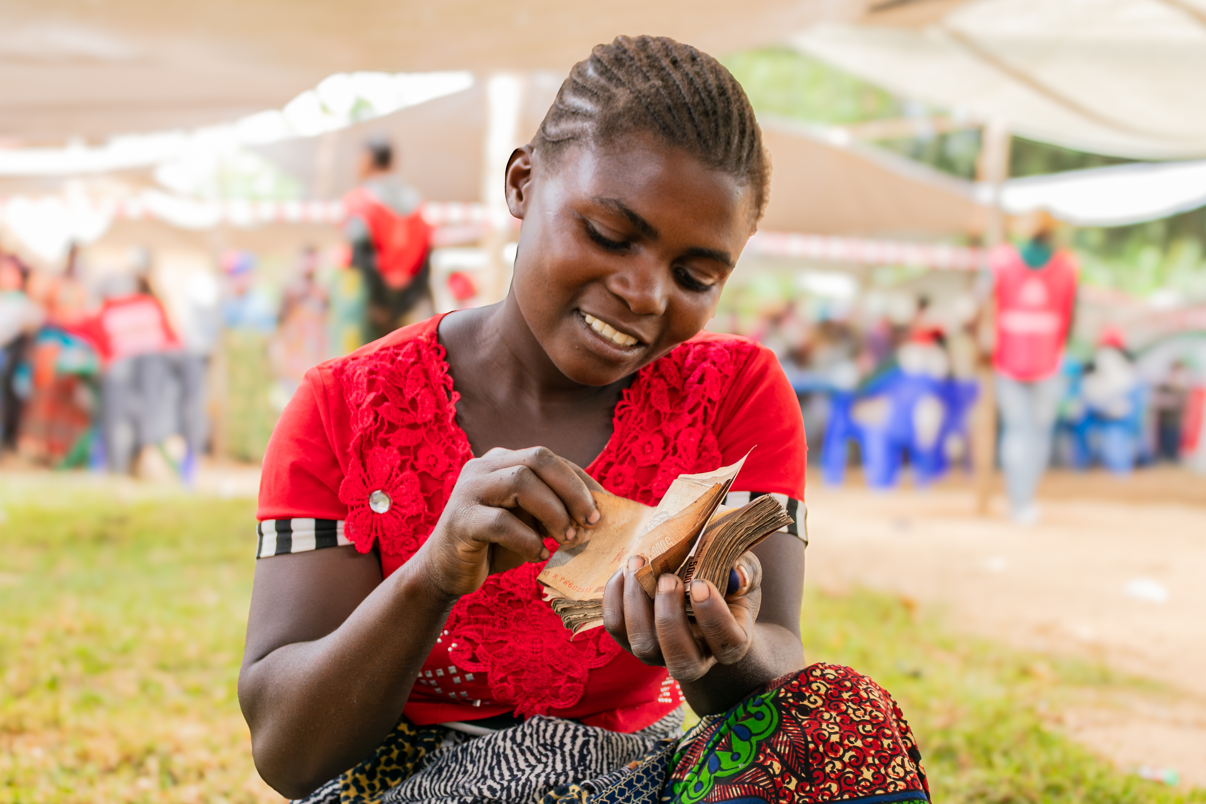 Woman sitting in open space among community members.