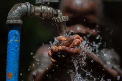 A young person washing their hands.