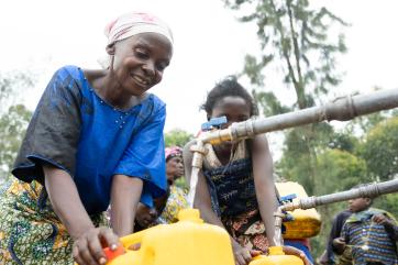 A person filling a jerrycan at a water spigot.