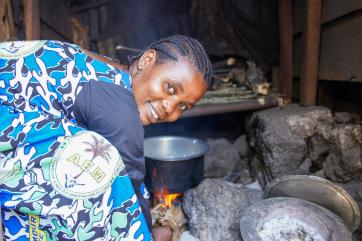 Drc woman cooking over open flame.