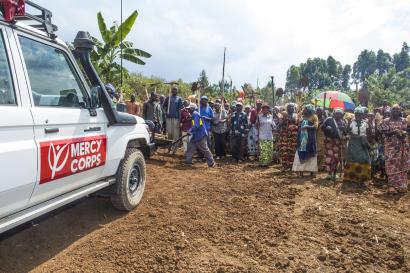 Mercy corps vehicle parked in front of community gathering.