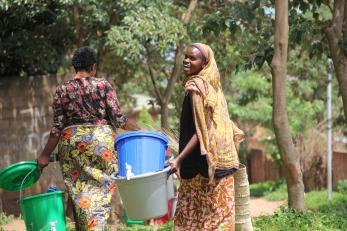 Congolese women gathering water, one smiling.