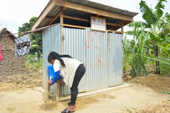 Woman collects water from public tap.