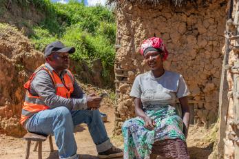 Drc individuals, one a mercy corps employee, sitting together outside the other's home.