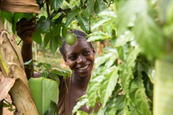 Congolese farmer standing within her crops, smiling.