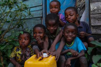 A group children sit together with a jerry can.