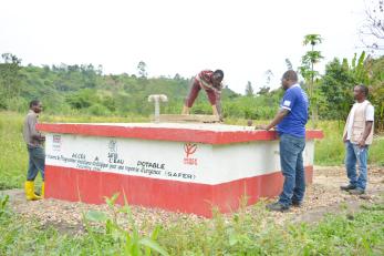 Four men work on a potable water well facility.