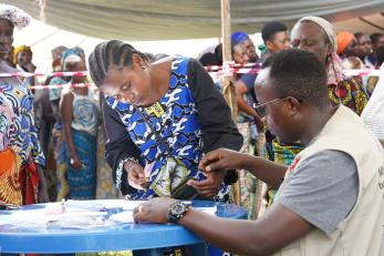 Two individuals in DRC work together at a table.