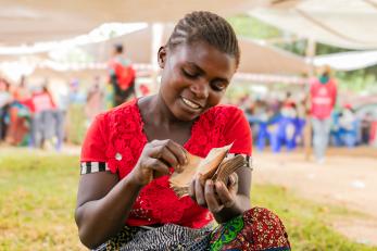 Woman sitting in open space among community members.