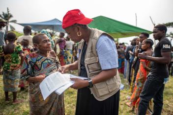 Une membre de l'équipe de communication parle à une femme pygmée déplacée qui attend de s'inscrire à une distribution pour les personnes déplacées.