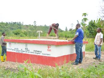 Four men work on a potable water well facility.