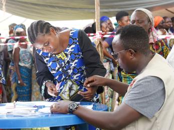 Two individuals in DRC work together at a table.