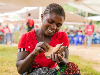 Woman sitting in open space among community members.